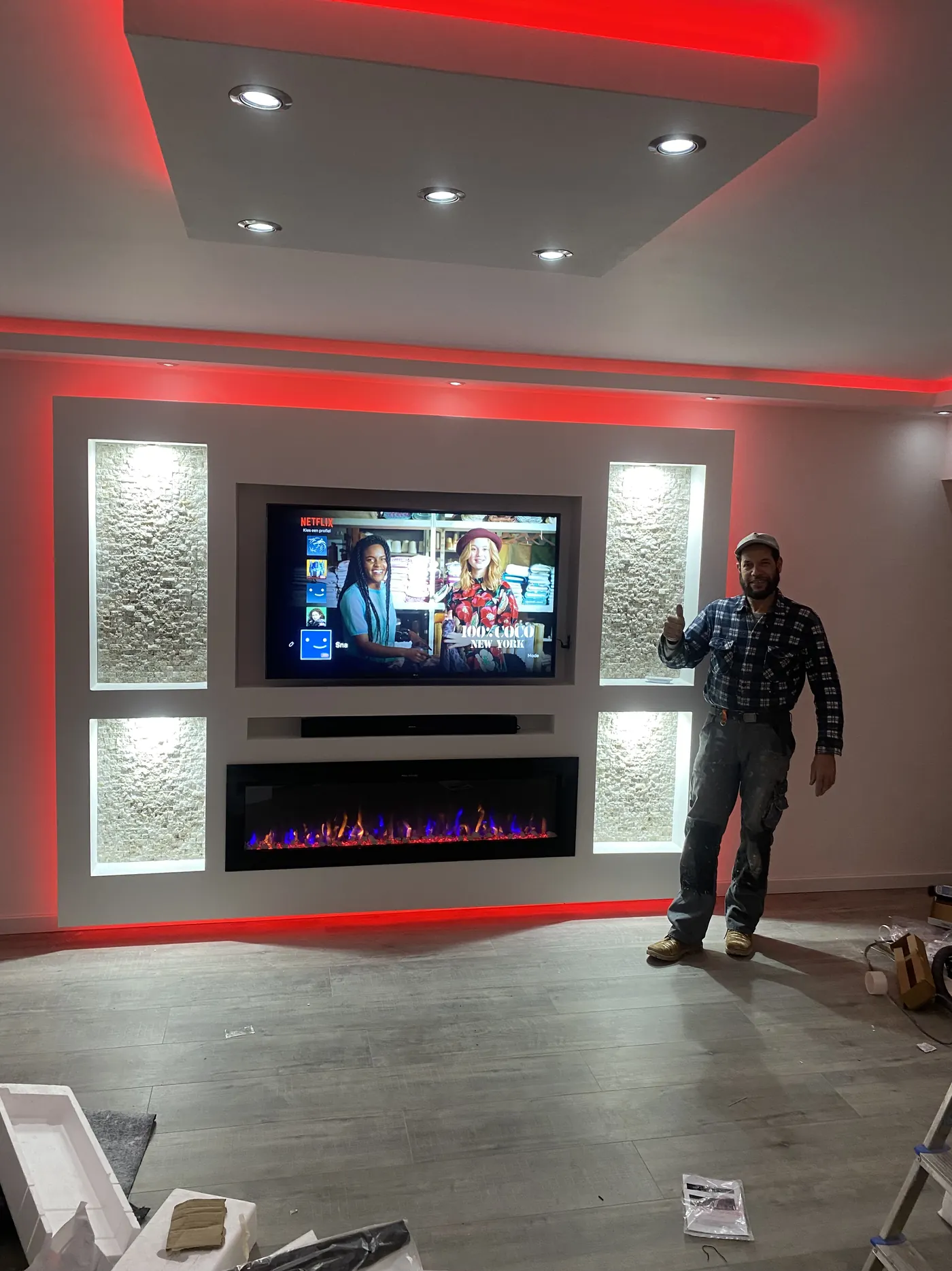 Witte cinewall met stenen zijpanelen, rode LED verlichting en elektrische haard, gemonteerd door vakman Naser